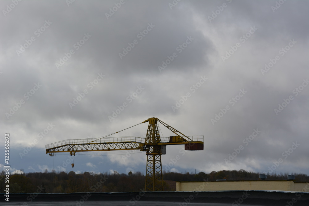 industrial landscape, lifting yellow crane on the background of gray sky, construction machinery, unloading, loading