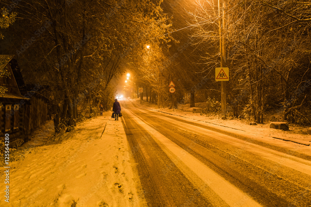 Evening in the small town. There is a heavy snow. Cars with lights going down the street. Evening in the small town. There is a heavy snow. Cars with lights going down the street.