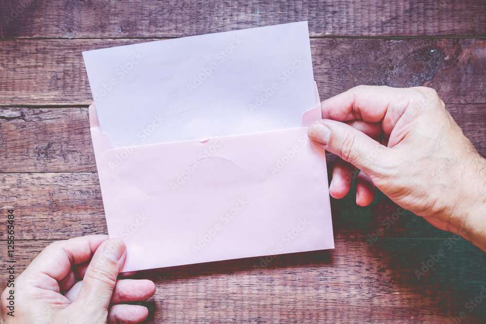 Obraz premium Hand hold a envelope and paper on the wooden background