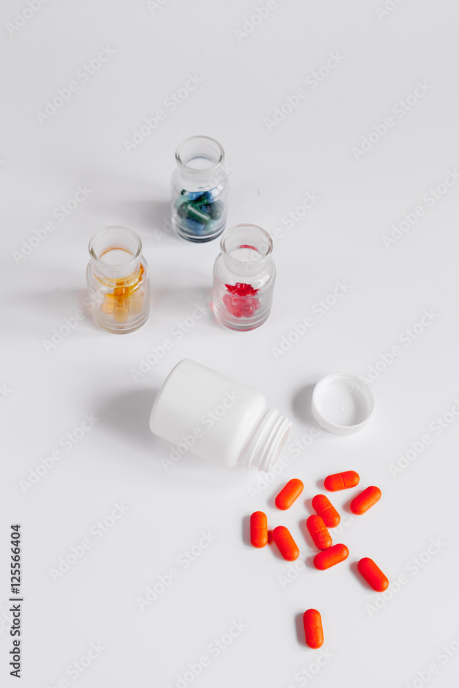 colored pills in glass bottles on white background colored pills in glass bottles on white background