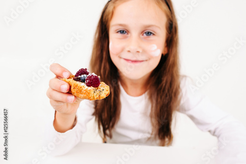 Girl treating you with berry cake  free space. Little smiling lassie propose sweet cookie to camera. Homemade bakery  children culinary  pastry making concept