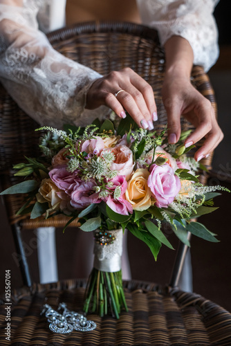 Wedding bouquet of the bride. Beautiful bride's gentle hands touched the bouquet leaves.