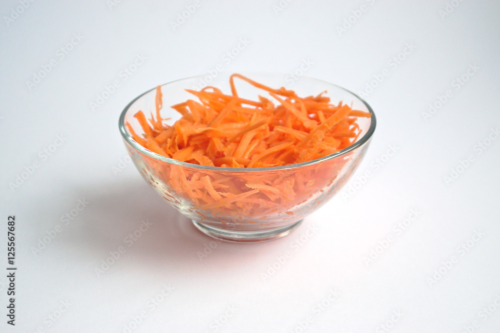Grated carrots in a bowl on a white background