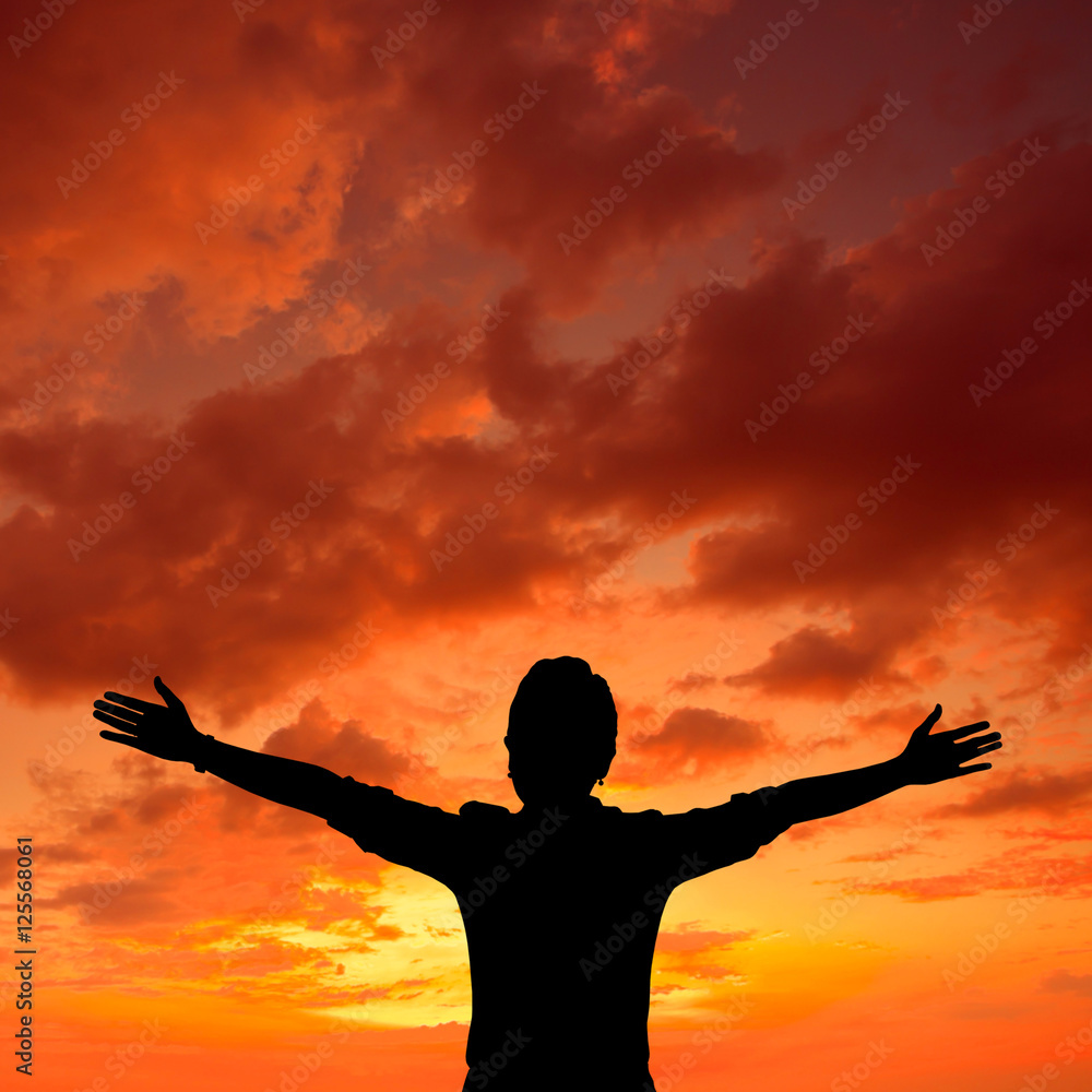 Woman silhouette raised hands over sunset sky
