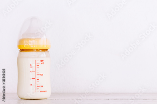 Baby bottle with milk on wooden table
