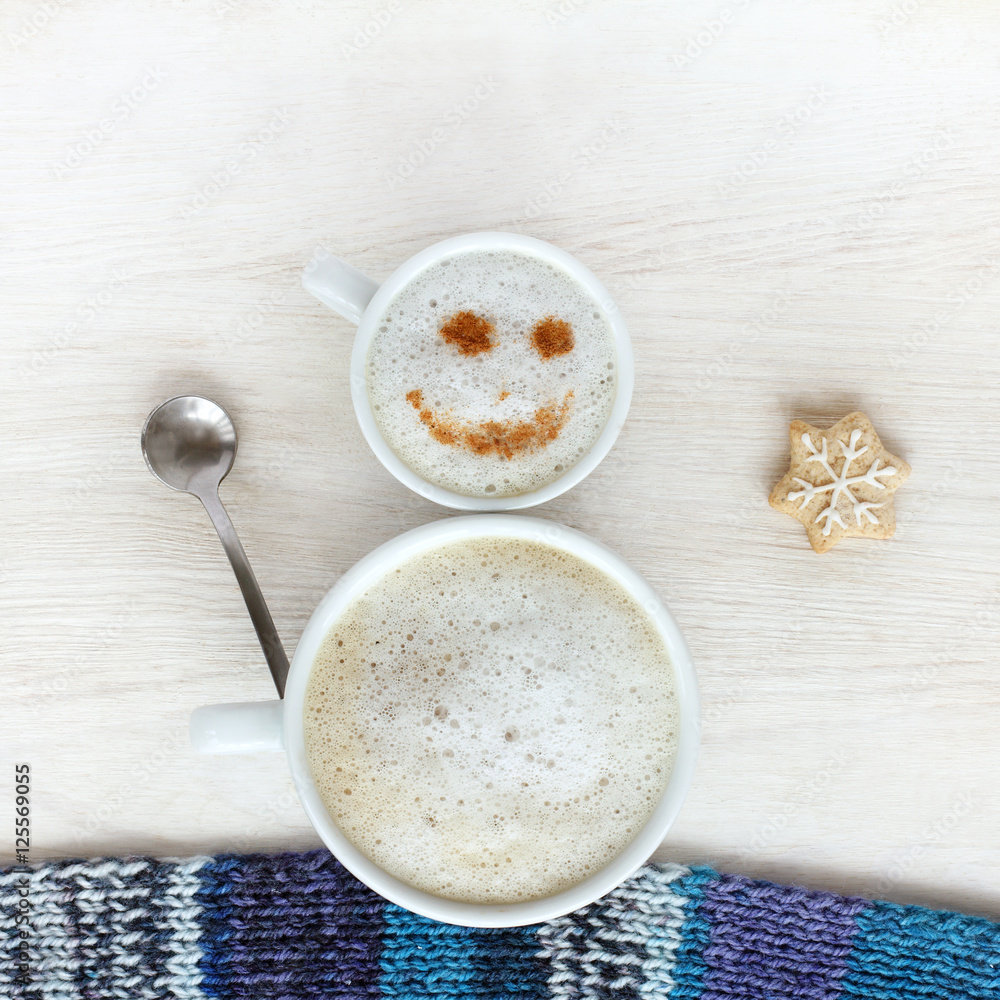 good mood for winter coffee break/ small and large cup of frothy cappuccino standing together in a cheerful snowman top view good mood for winter coffee break/ small and large cup of frothy cappuccino standing together in a cheerful snowman top view
