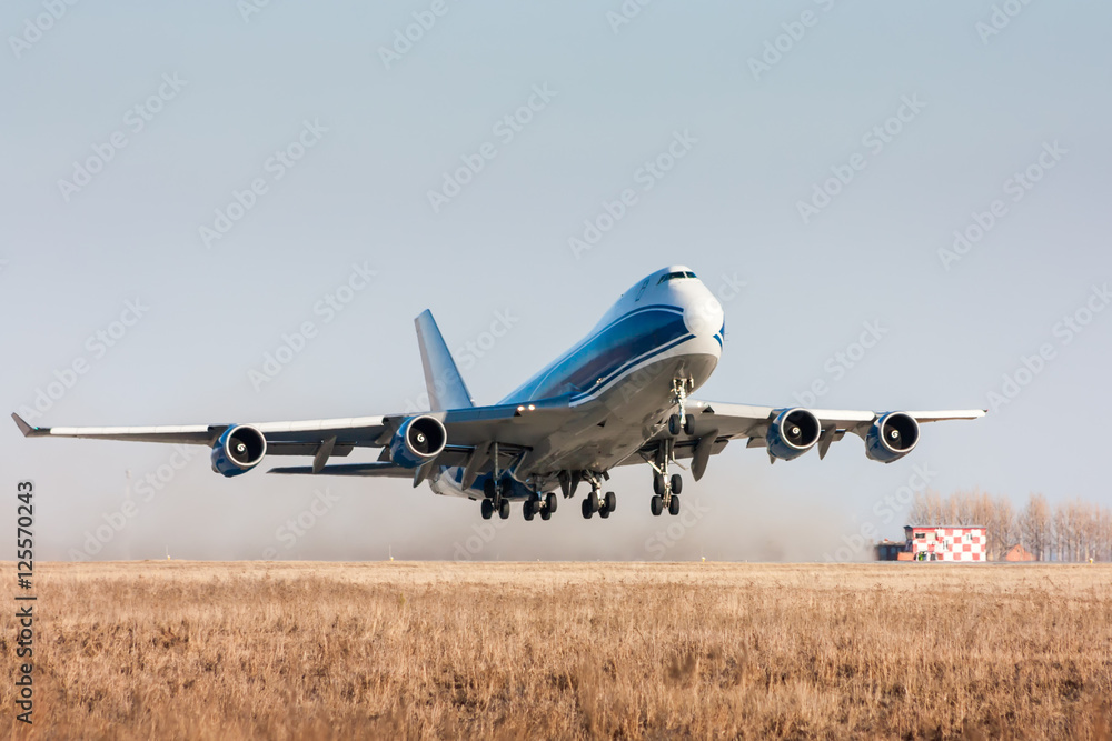 Obraz premium Wide body cargo airplane takes off leaving behind a cloud of dust