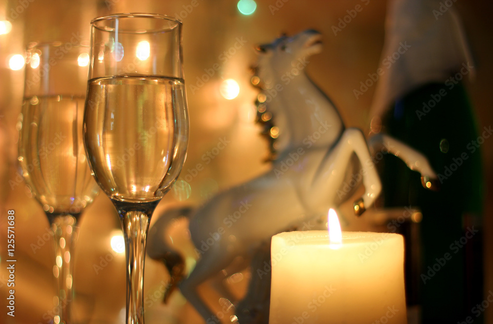 Style New Years Eve celebration background with horse an elegant arrangement with a flutes and bottle of champagne and party streamers with a candles.