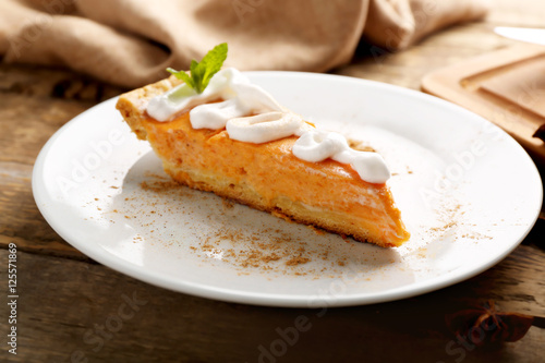 Slice of delicious pumpkin cake with cream decoration on plate