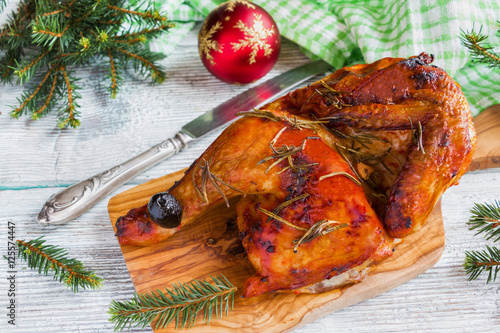 Half of chicken, baked in oven with black olives in oil, Christmas decoration, wooden background, top view.