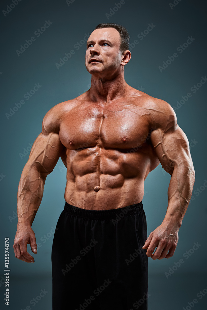 torso of attractive male body builder on gray background. torso of attractive male body builder on gray background.