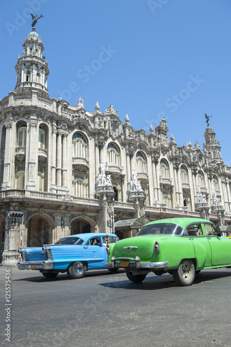 Brightly colored vintage American cars pass in front of the landmark architecture of the Great Theater of Havana, Cuba © lazyllama