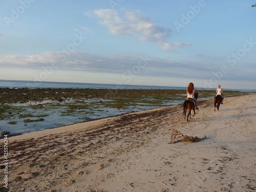 Women riding on horseback on the beach at sunset. Gili. Indonesia
