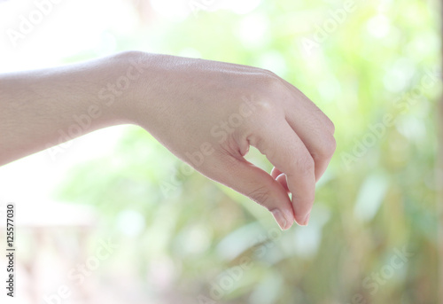 The female hand on a green background reaches for something © naiauss