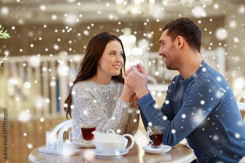 happy couple with tea holding hands at restaurant