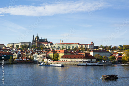 Prague Castle, Hradcany, Prague, Czech Republic / Czechia - panorama of historical part of the city. Dominant towers of Saint Vitus Cathedral. Boats with tourists on the Vltava river