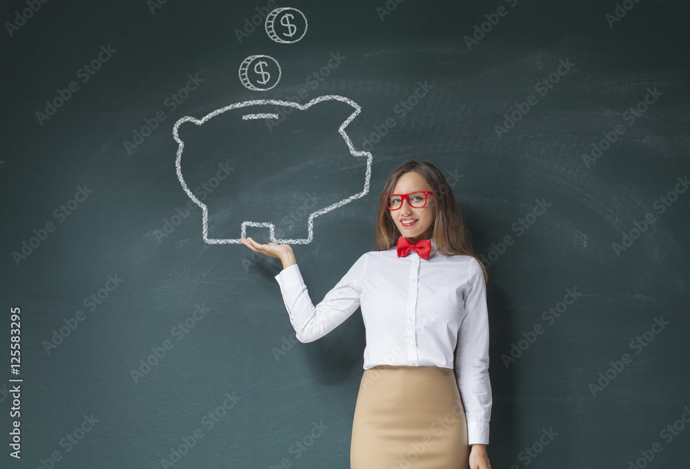 Holding piggy bank drawing front of blackboard