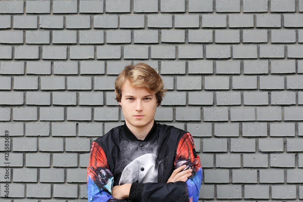 Portrait of attractive teenage boy standing in front of a brick wall. Portrait of attractive teenage boy standing in front of a brick wall.