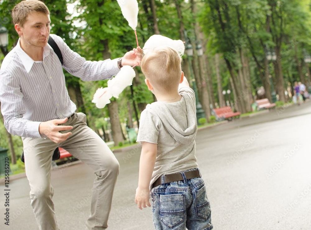Fototapeta premium baby boy eating cotton candy with his father
