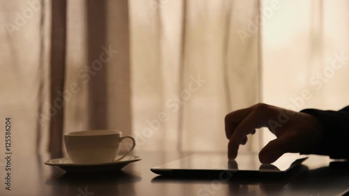 Man Using Tablet PC and Drinking Coffee in Cafe