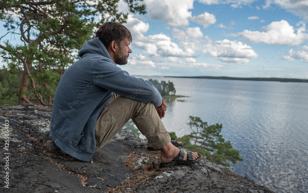 Man is sitting on the rock and looking into the distance Man is sitting on the rock and looking into the distance
