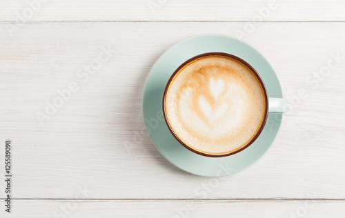 Cappuccino foam, coffee cup top view on white wood background