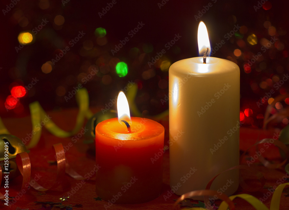 Christmas and New Year`s festive evening burning candle bokeh image. Greeting card  lights Background concept with holiday tinsel, twisted ribbons and copyspace place for text or logo.