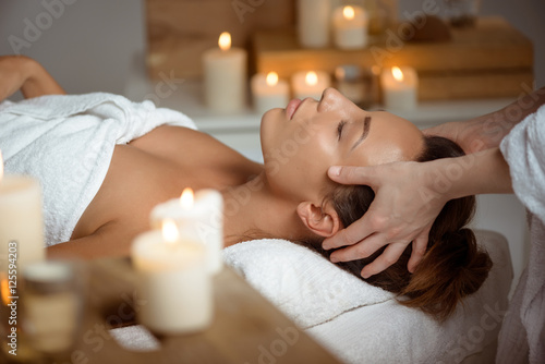 Young beautiful girl having face massage relaxing in spa salon. photo