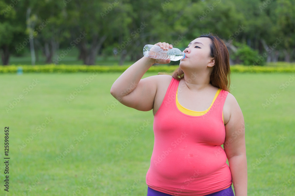 Beautiful fat woman drinking water after finish her workout. Beautiful fat woman drinking water after finish her workout.