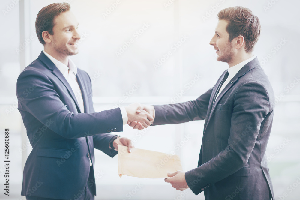 Businessmen shaking hands with friendly smiles Businessmen shaking hands with friendly smiles