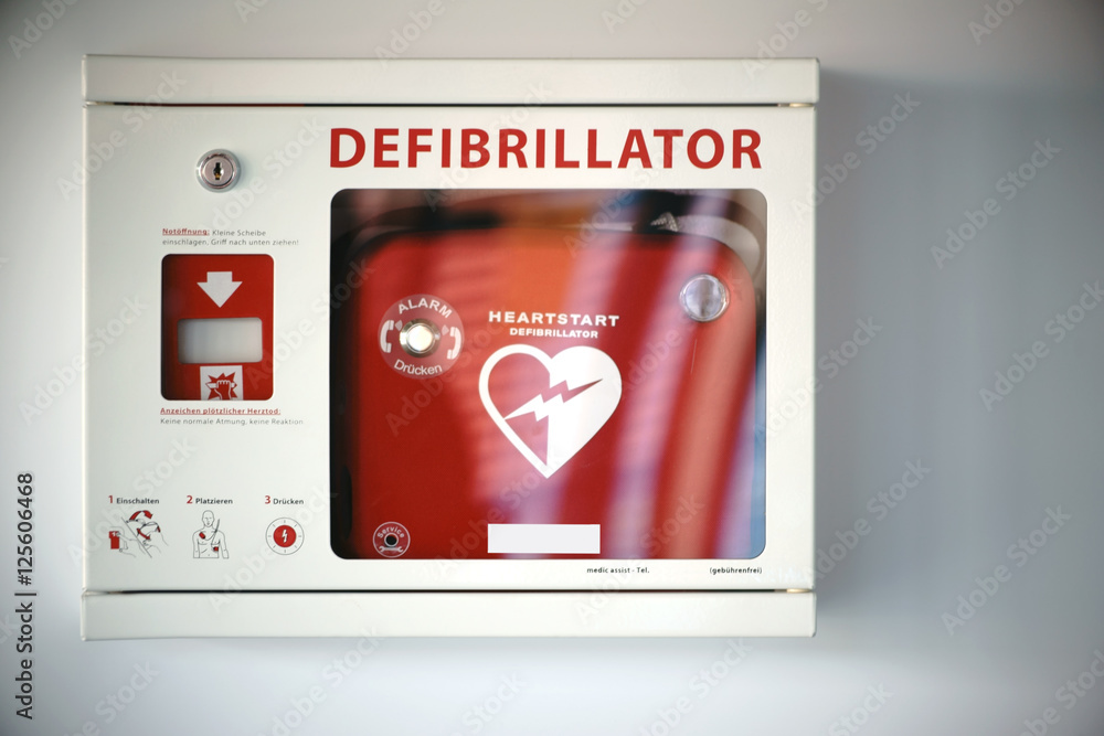 Defibrillator / Ein Überlebenskasten mit einem Defibrillator an einer Wand eines öffentlichen Gebäudes. - obrazy, fototapety, plakaty 