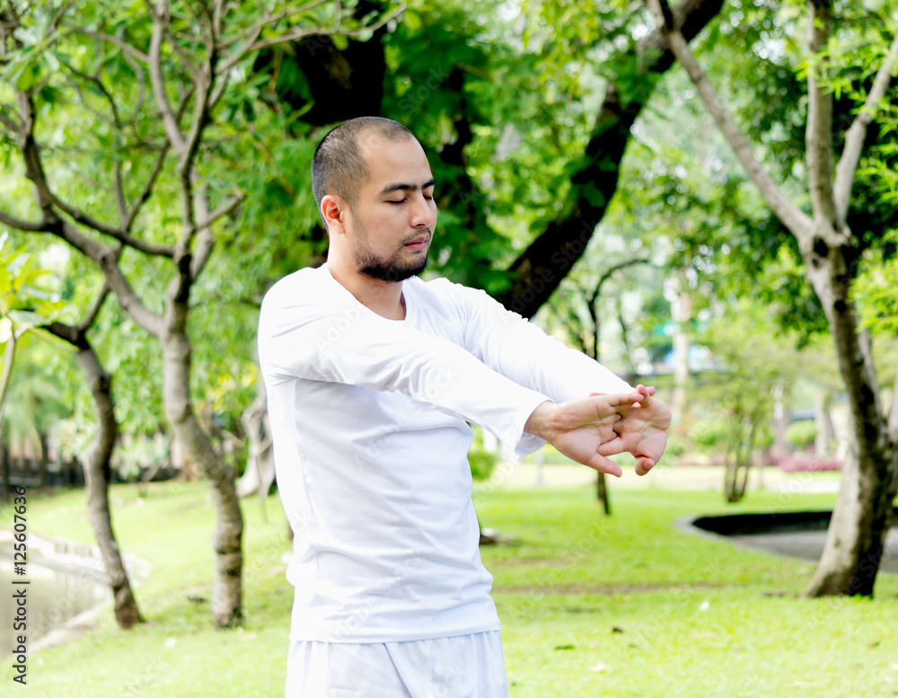 An asian man standing and close his eyes stretching, relaxing before exercise An asian man standing and close his eyes stretching, relaxing before exercise