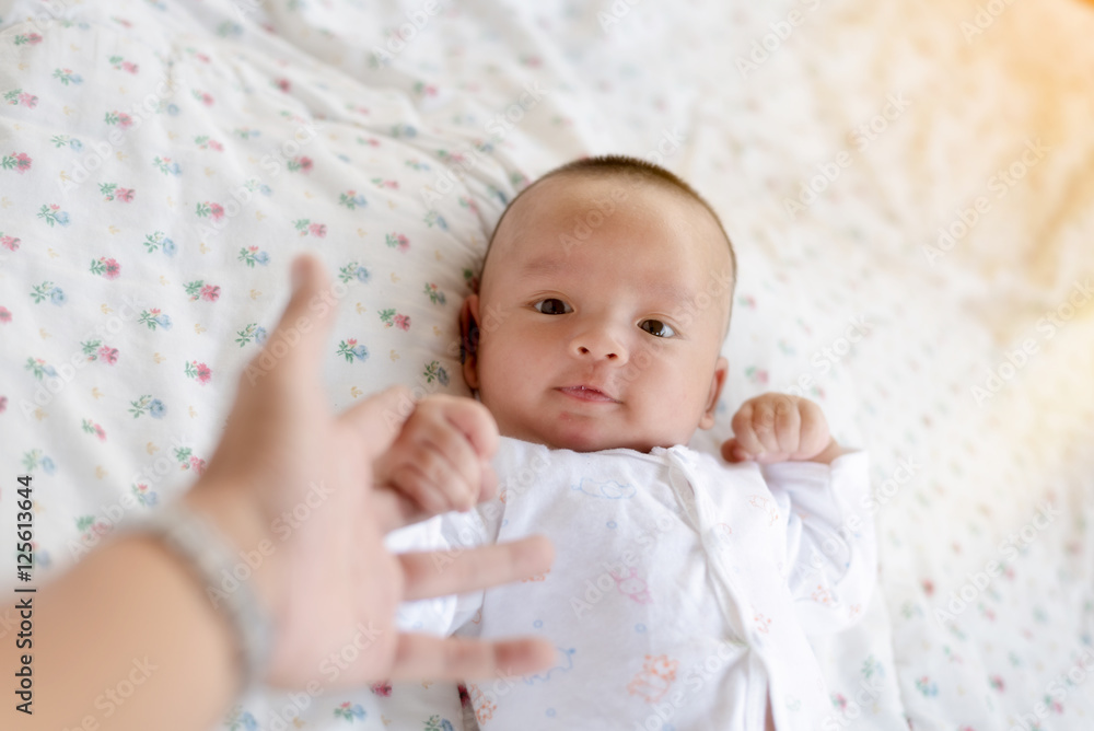 The baby was lying on a white bed . That baby was teasing by his cute father and sister .This Image is showing very good relationships between family members. The baby was lying on a white bed . That baby was teasing by his cute father and sister .This Image is showing very good relationships between family members.