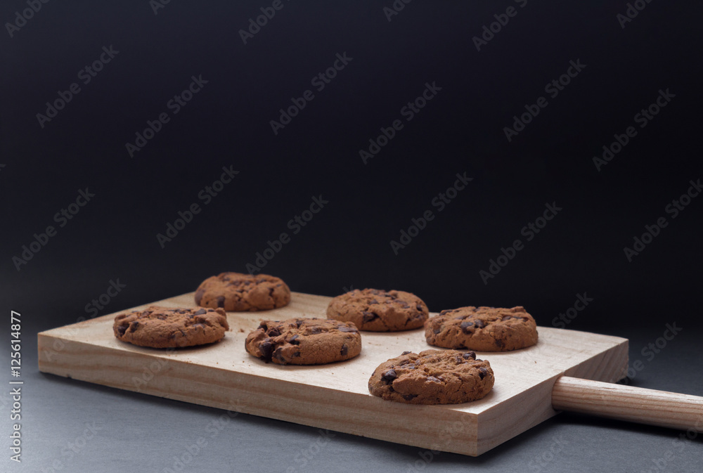 Chocolate cookies on a wooden cutting board. Black background.
Chocolate cookies on a wooden cutting board. Black background.