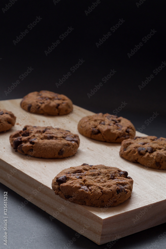 Chocolate cookies on a wooden cutting board. Black background.
