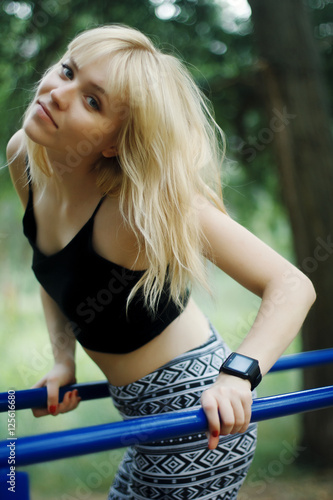 Молодая девушка блондинка выполняет упражнения на брусьях 