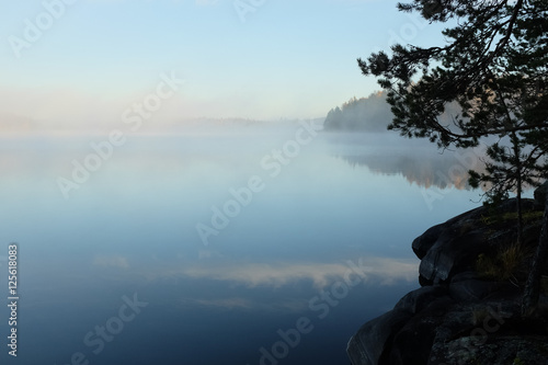 Beautiful lake view in early morning light and mist on lake surface, Finland.