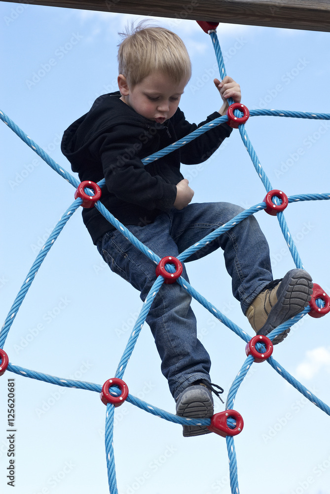 Little child blond boy climbing rope on the playground outdoors
Little child blond boy climbing rope on the playground outdoors
