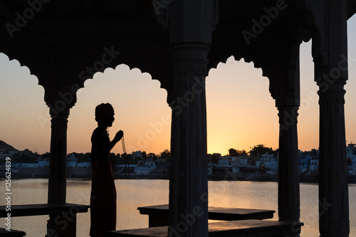 Canvas Print Silhouette of a sadhu performing ritual prayer in the evening at Pushkar Lake