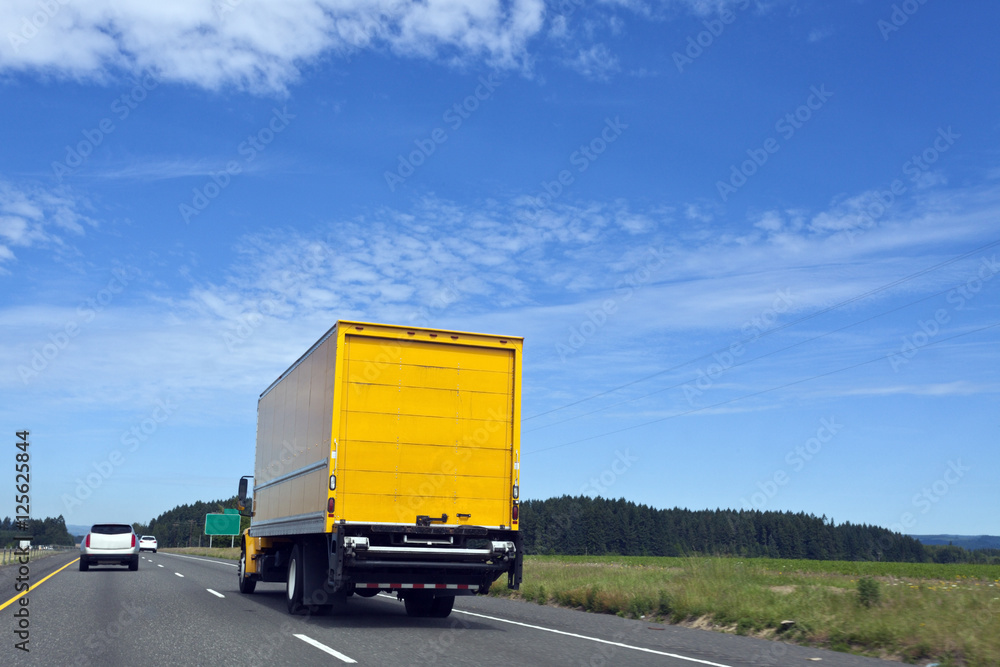 Rear view of bright yellow semi trailer on highway