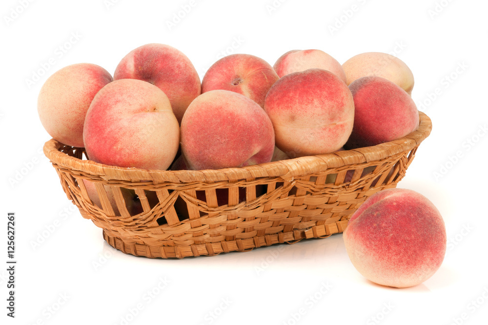 peaches in a wicker basket isolated on white background