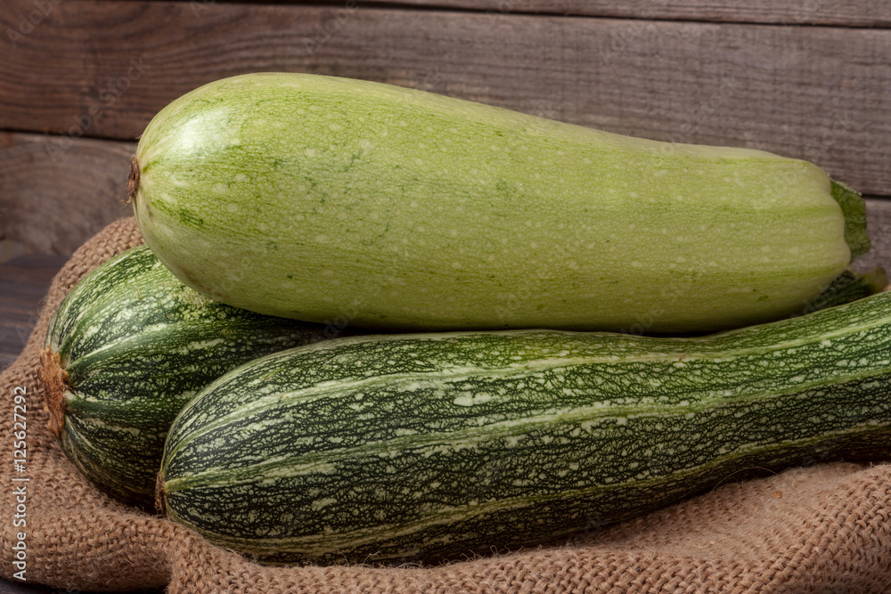 green zucchini and courgettes on sackcloth wooden background green zucchini and courgettes on sackcloth wooden background
