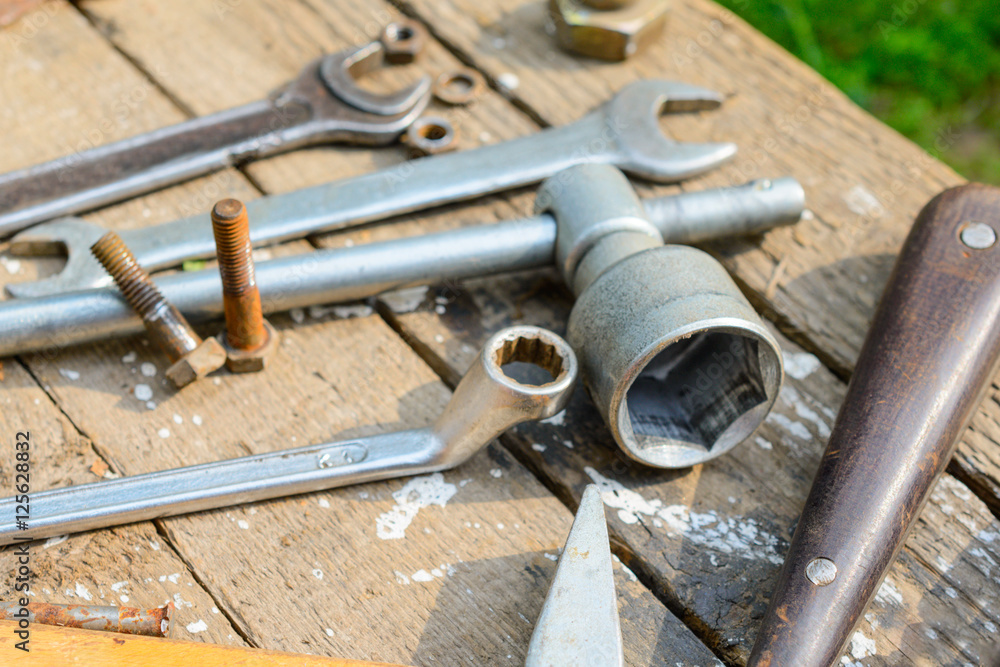 On weathered old wooden surface lie the , oily wrenches. On weathered old wooden surface lie the , oily wrenches.