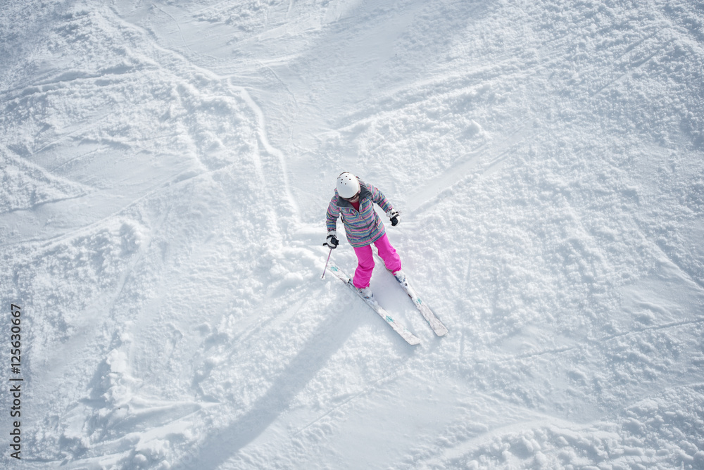 Woman in colorful ski suit, skiing down the mountain.