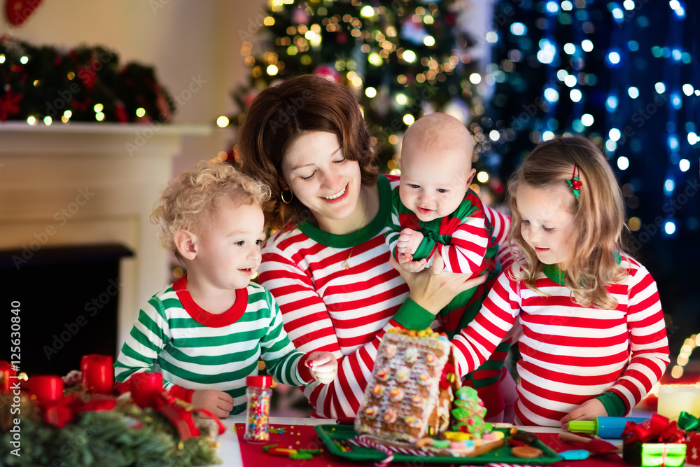 Mother and kids making ginger bread house on Christmas Mother and kids making ginger bread house on Christmas