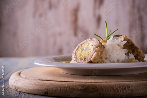 Single portion of meat roll filled by eggs and bacon with rice