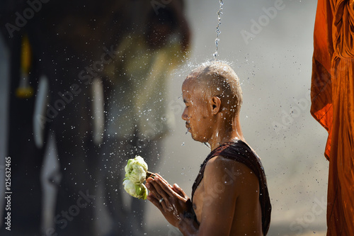 Portrait of a monk pouring water on another monks head, Thailand photo