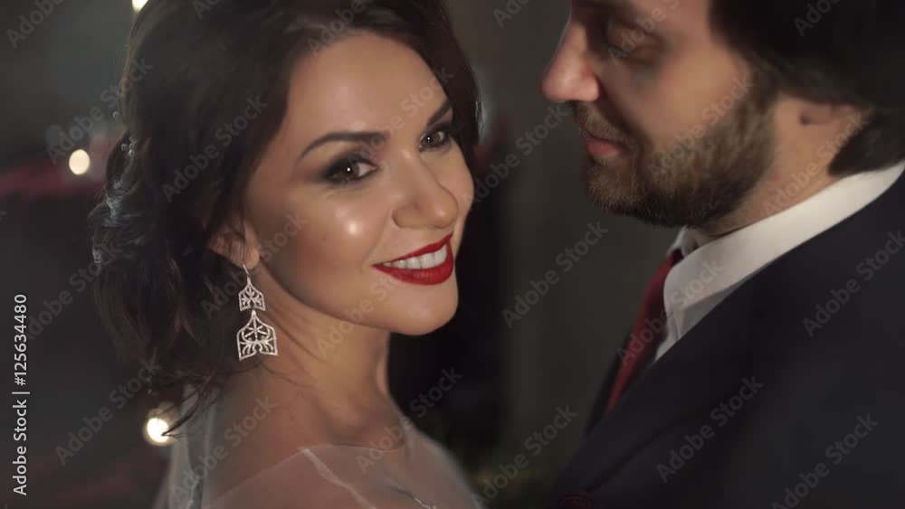 Amazing beautiful woman with red lips smiling broadly snow-white smile, as her husband hugs her gently. Amazing beautiful woman with red lips smiling broadly snow-white smile, as her husband hugs her gently.