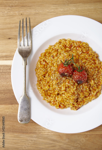 A dinner bowl of tomato risotto on a wooden table background