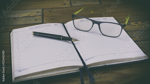 diary and glasses, diary on a wooden background Ballpoint pen